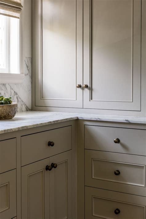 A White Kitchen With Marble Counter Tops And Cabinets In Front Of A