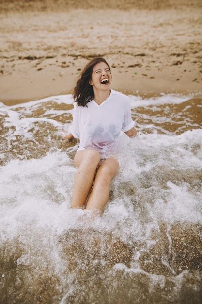 Premium Photo Happy Young Woman In Wet White Shirt Lying On Beach In