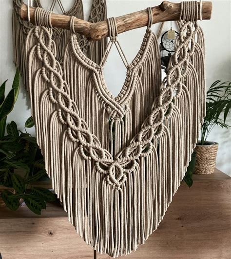 A Macrame Hanging On A Wall Next To A Clock And Potted Plant