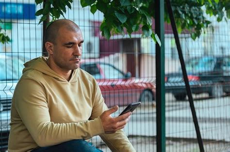 Hombre fuerte sentado en un banco y mirando su teléfono Foto Premium