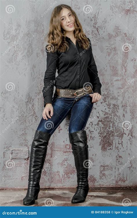 Young Girl With Curly Hair In A Black Shirt Jeans And High Boots