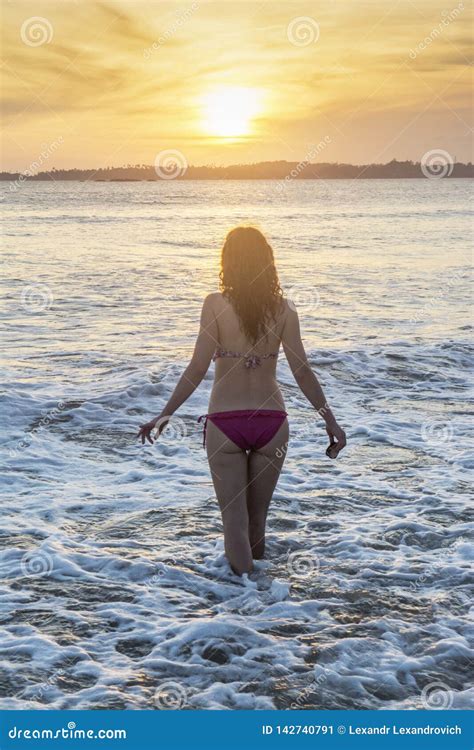 Pretty Girl In Pink Bikini Standing On The Beach During Sunset Stock