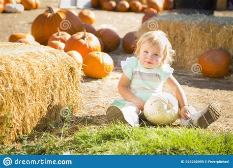 Adorable Baby Girl Having Fun In A Rustic Ranch Setting At The Pumpkin