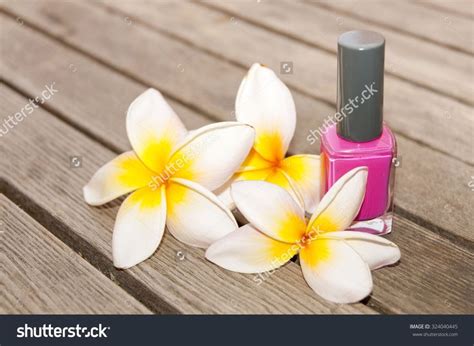 Fuchsia Nail Polish In The Bottle And Flowers On The Woody Background