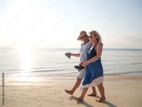 Two Funny Older Women Walking And Laughing At Coast Line At Sunny Day