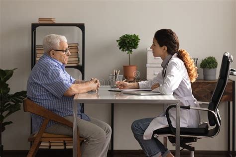 Older Man Patient Meeting Woman Attending Physician For Medical Checkup