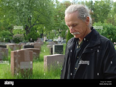 Sorrowful man standing in cemetery with head bowed Stock Photo - Alamy