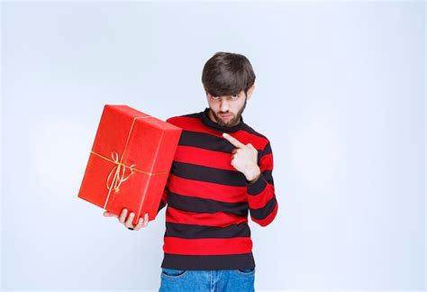 Hombre De Camisa A Rayas Rojas Sosteniendo Una Caja De Regalo Roja Y