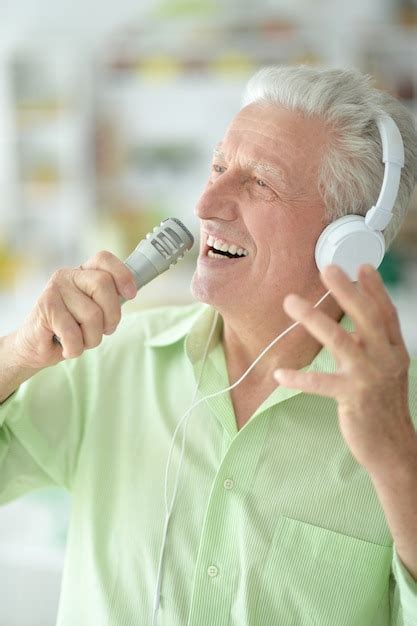 Premium Photo Senior Man In Headphones Singing Into Microphone