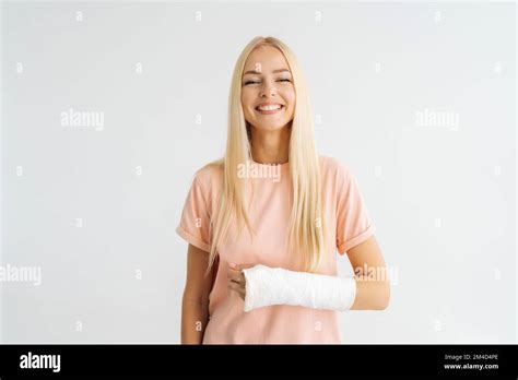 Studio Portrait Of Positive Blonde Young Woman With Broken Arm Wrapped