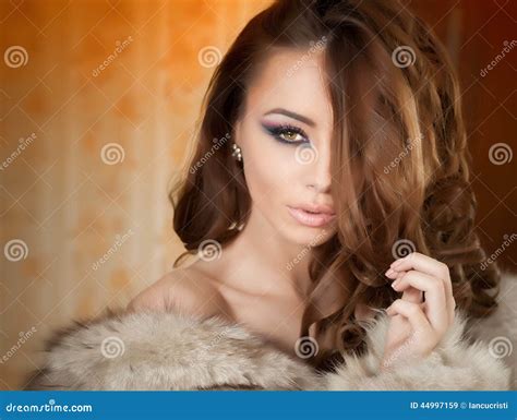 Attractive Young Woman Wearing A Fur Coat Posing Provocatively Indoor