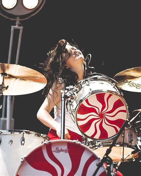 A Woman With Long Hair Playing Drums In Front Of A Red And White Candy