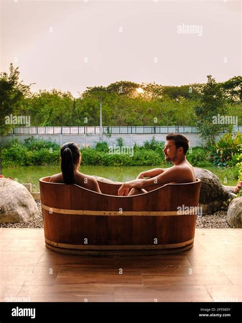 Couple Men And Women In Wooden Bathtub At The Countryside Of Thailand Watching Sunset Stock