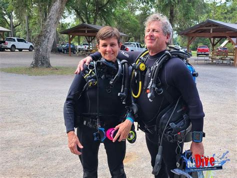 Two People Wearing Scuba Gear Standing Next To Each Other