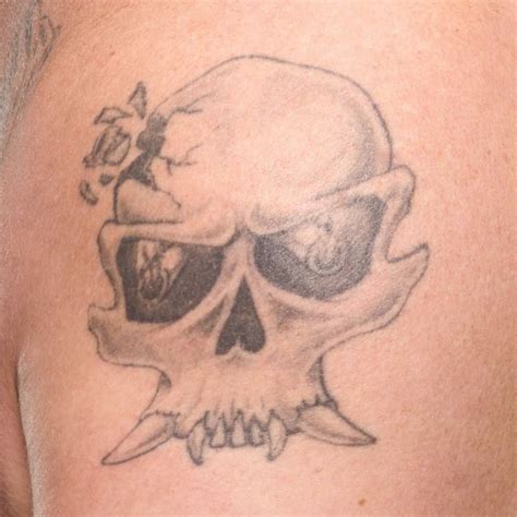 A Close Up Of A Person S Shoulder With A Skull Tattoo On It