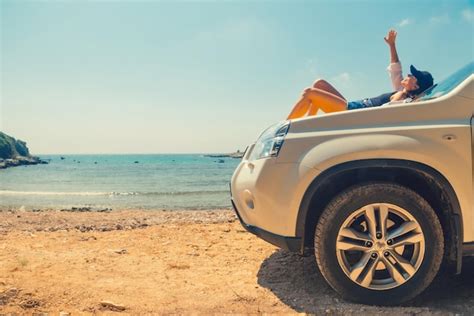 Mulher feliz na praia de verão do mar sentado no capô do carro Foto