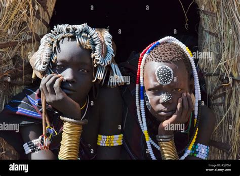 Mursi tribe, people in traditional clothing in front of traditional ...