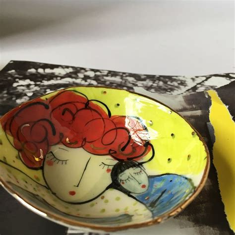 A Yellow Plate With A Painting On It Next To A Piece Of Torn Up Paper