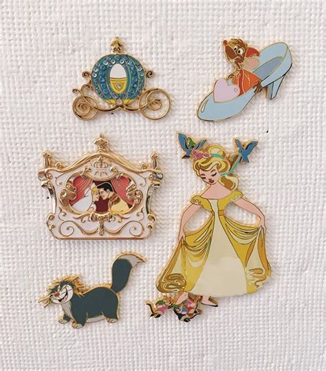 Four Disney Princess Pins Sitting On Top Of A White Towel Next To Each