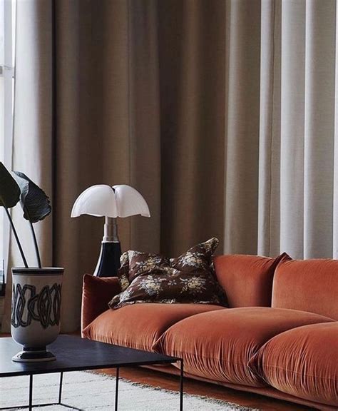 a bold rust colored velvet sofa with soft cushions and pillows will brighten up your living ...