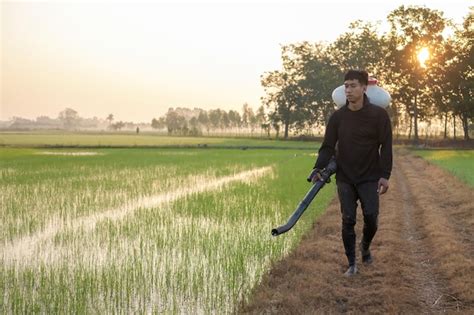 Premium Photo A Farmer From Asia Is Using A Knapsack Mist Duster To