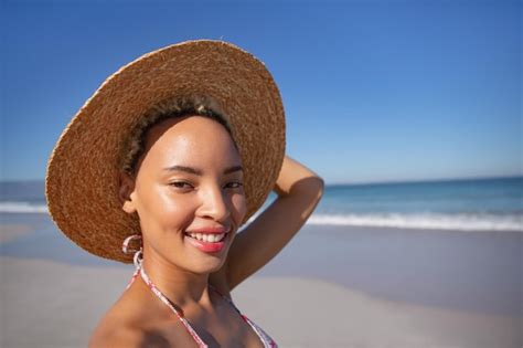 Premium Photo Happy Woman In Bikini And Hat Looking At Camera On Beach In The Sunshine
