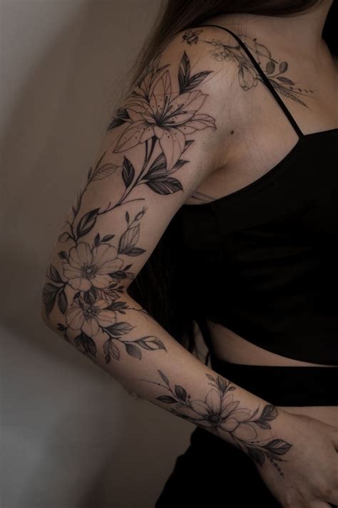 A Woman S Arm With Flowers And Leaves Tattooed On Her Left Arm Behind