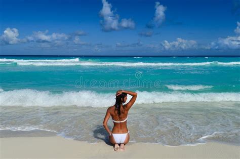 A Menina Senta Se Na Praia Do Mar Em Um Biquini Branco Imagem De Stock