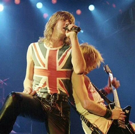 Two Men On Stage With Guitars And Microphones In Their Hands One Holding The Other