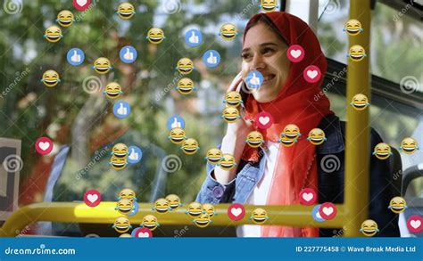 Animation Of Od Falling Emojis Over Woman In Hijab Using Smartphone