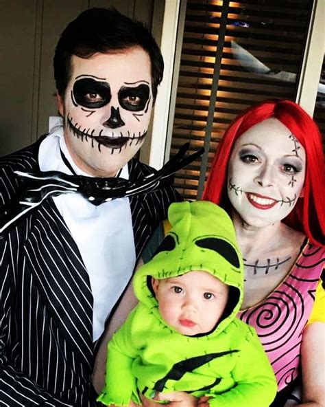 A Man And Woman In Halloween Costumes Holding A Baby