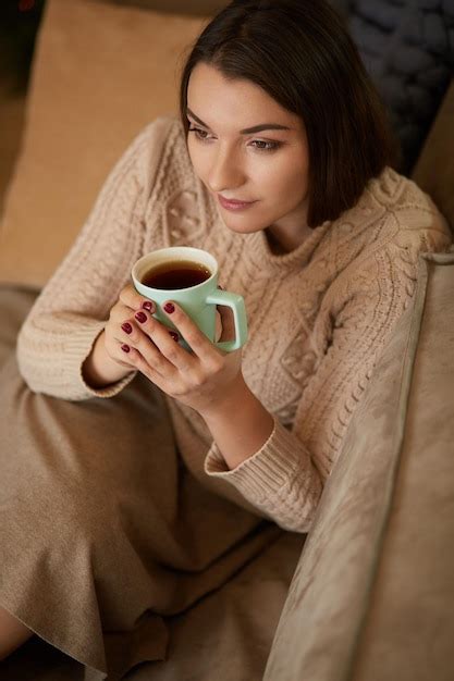 Premium Photo Happy Young Woman Sitting On Sofa Holding A Mug At Home