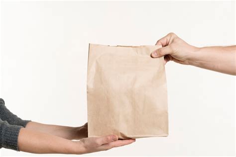 Premium Photo | Front view of pair of hands holding paper bag