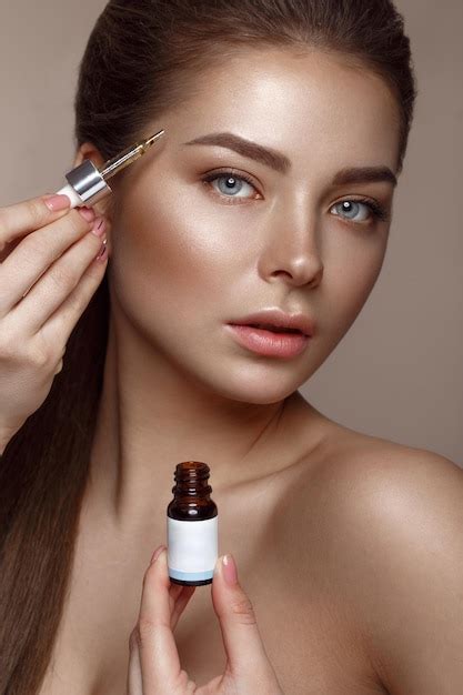 Hermosa joven con maquillaje nude natural con cosmético en las manos