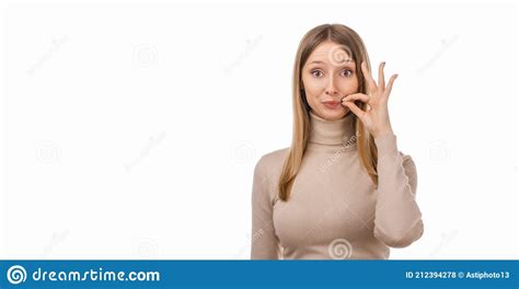 Blond Girl In Casual Clothes Showing Zip Gesture As If Shutting Mouth