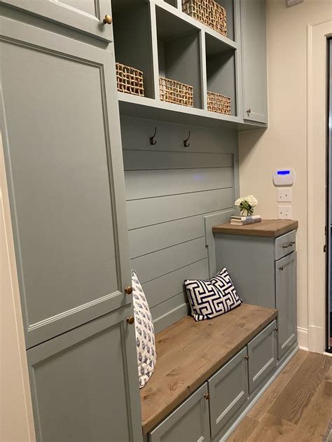 A Mud Room With Gray Cabinets And Wooden Bench In The Center Along