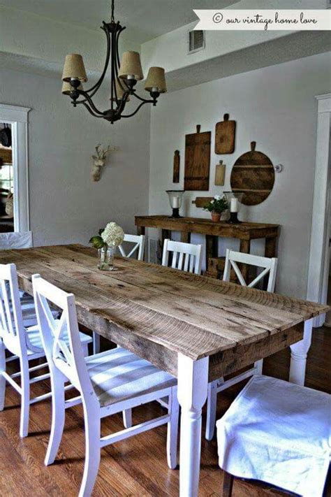 A Dining Room Table With White Chairs And A Chandelier