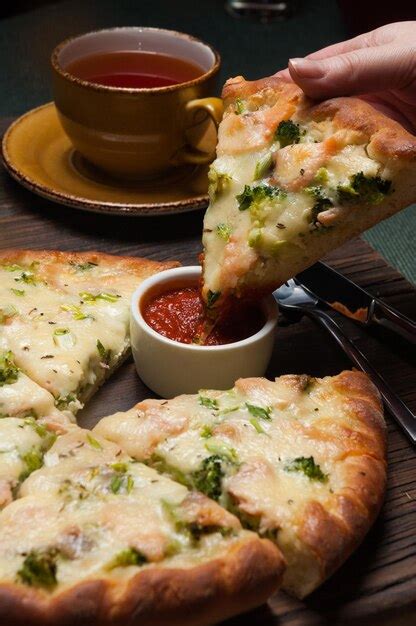 Premium Photo | Girl dips a slice of pizza with salmon and broccoli in ...