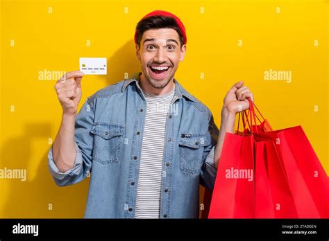 Photo Of Cheerful Impressed Guy Wear Denim Jacket Rising Bargains Showing Credit Card Isolated