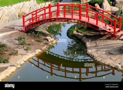 Old red wooden bridge across a small river in a green park. Vintage ...