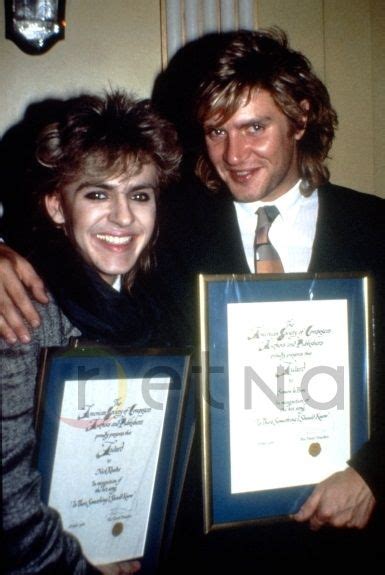 Two People Posing For The Camera While Holding Up Their Awards And