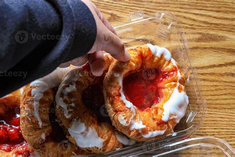 A Mans Hand Is Holding A Cherry Filled Danish Or Danish Bread In A