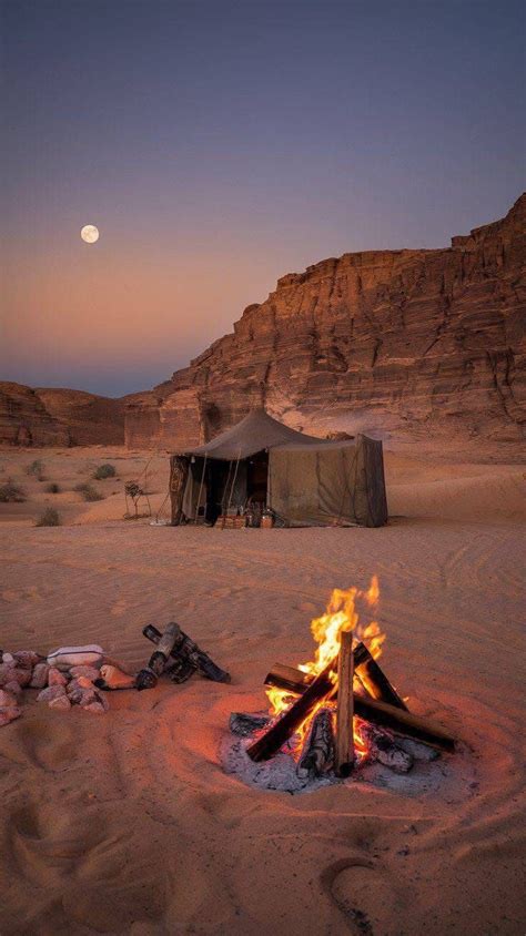 A Camp Site In The Desert With A Full Moon Setting Behind It And Rocks