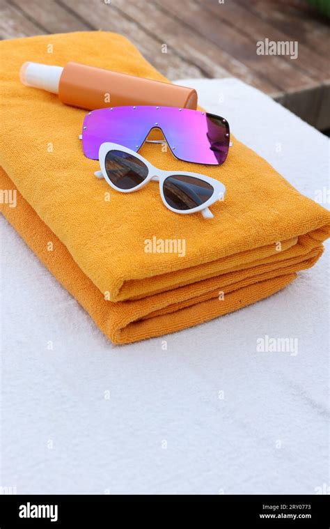 Beach Towels Sunglasses And Sunscreen On Sunbed At Resort Stock Photo