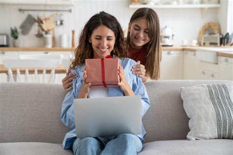 Una joven sonriente y feliz sentada en el sofá recibiendo una caja de