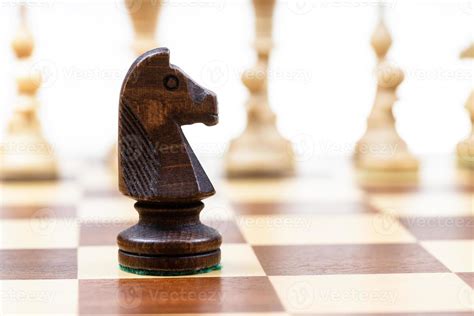 black knight against white chess pieces on board 20501330 Stock Photo ...