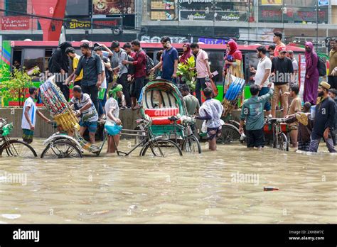 Commuters Wade Through A Waterlogged Road After Heavy Rainfall In Dhaka