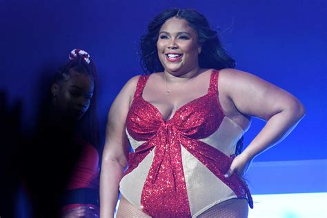 Lizzo dazzles in sparkling sexy leotard wrapped in festive red bow at ...