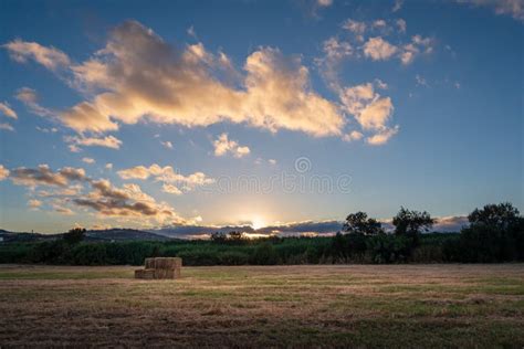 Hay on a Field during a Sunset with Clouds and the Sun Stock Image ...