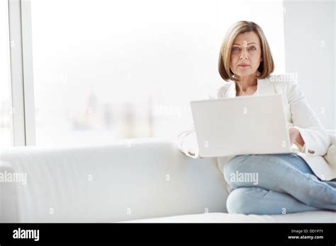 Portrait Of Mature Woman With Laptop Sitting On Sofa And Looking At Camera Stock Photo Alamy